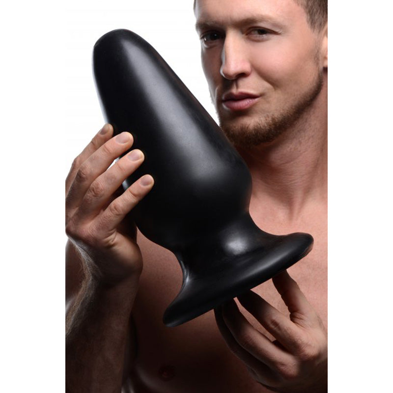 Man holding XR Brands AF837 Master Cock Gigantor XXXL Tapered Butt Plug over a white background